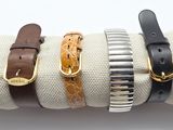four different leather bracelets on a napkin with a gold buckle