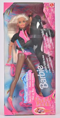 La poupée Barbie se trouve dans une boîte rose ornée d'un orque en noir et blanc.