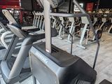 rows of tread machines in a gym with a television on the wall