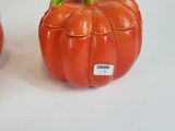 two orange pumpkins sitting next to each other on a white surface