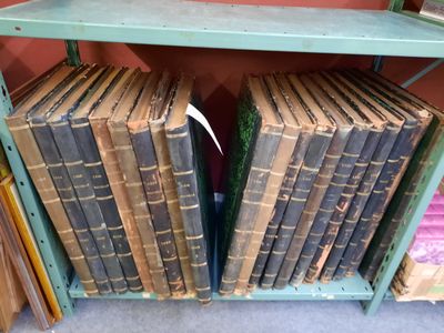 Des livres sont empilés sur une étagère dans une pièce dont l'un des murs est rouge.