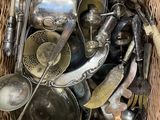 un panier en osier rempli de vieux couverts et ustensiles en argent