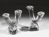 une paire de bougeoirs en verre transparent posés sur une surface blanche