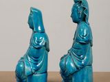 pair of blue ceramic figurines of a woman and a man sitting on a stool