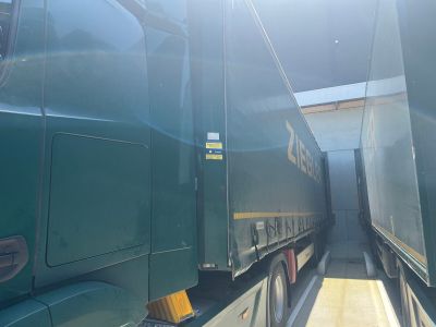 two green semi trucks parked side by side in a parking lot