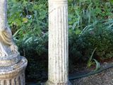 a statue of a woman holding a bird next to a pillar