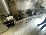 une personne debout dans une cuisine, à côté d'une cuisinière et d'un four