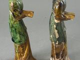 three ceramic figurines of a woman and a bird on a gray surface