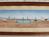 framed picture of a painting of a desert scene hanging on a brick wall