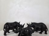 three black rhino figurines sitting on a white surface