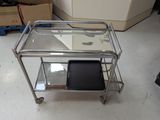 a metal cart with a glass top on the floor