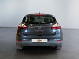 the back end of a grey car in a room with a white wall