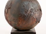 a metal sculpture of a ball on a wooden base