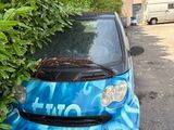 a small blue car that is parked next to a bush