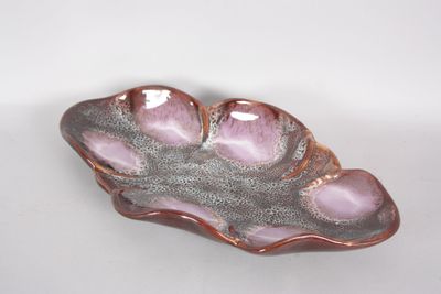 a pink and silver leaf shaped dish on a white table
