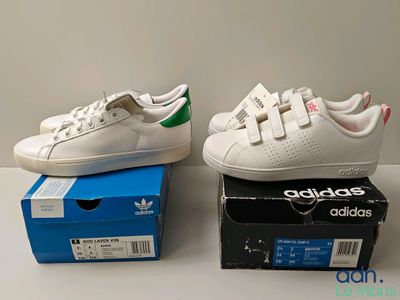 deux paires de baskets Adidas blanches posées sur une boîte