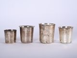 quatre coupes en argent sont alignées sur une surface blanche