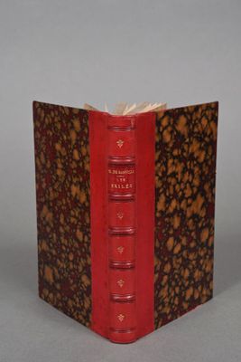 an old book with a red cover sitting on top of a table
