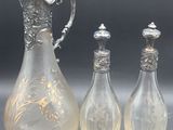 trois vases en verre et un pichet en métal argenté posés sur une table