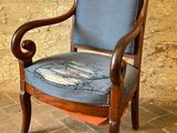 une chaise en bois avec une assise rembourrée bleue, posée sur un sol en briques