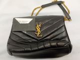 a black handbag with a gold chain strap and a tag on it