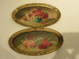 two oval paintings with flowers on them on the wall
