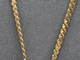 a close up of a necklace with a gold chain on a gray surface