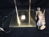 a statue of a man holding a lamp next to a mirror