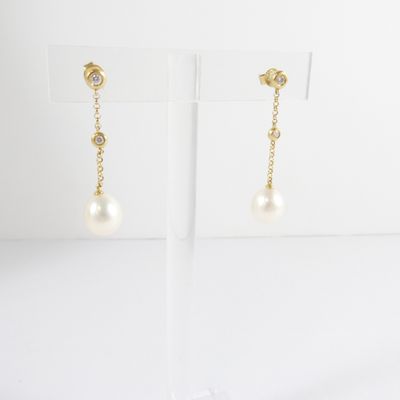 a pair of pearl and gold earrings on a stand