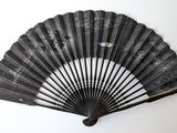 an old black fan hanging on a wall next to a white wall