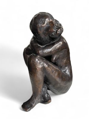 statue en bronze représentant un enfant assis à genoux sur un fond blanc