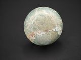 a green and white marble ball on a black surface