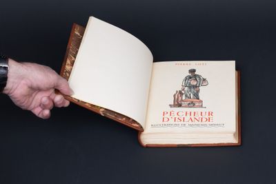 quelqu'un tient un livre ouvert sur lequel figure la photo d'un homme