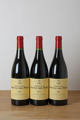 trois bouteilles de vin rouge sont posées sur une table en bois