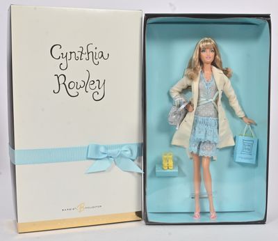 La poupée Barbie se trouve dans une boîte ornée d'un ruban bleu