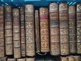 many old books stacked on top of each other in a crate