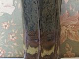 a vase sitting on a table with a floral wallpaper behind it