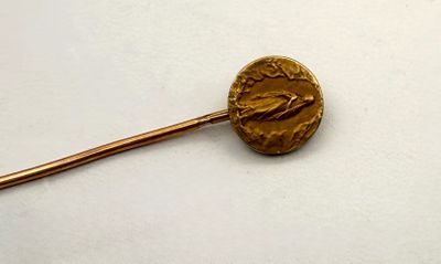 une pièce d'or fixée à un bâton posé sur une surface blanche