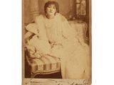 an old photo of a woman sitting on a couch with a teddy bear