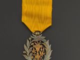 a close up of a medal on a black surface with a yellow ribbon