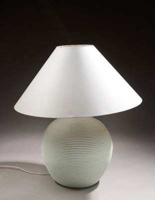 une lampe posée sur une table, munie d'un abat-jour blanc