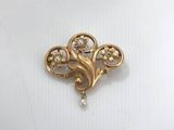 a close up of a gold brooch with pearls on it