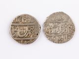 two silver coins with arabic writing on them on a white surface