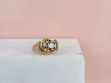 une bague en or et diamants posée sur un bloc de marbre blanc