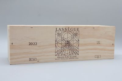 La boîte en bois contient une bouteille de vin et une autre boîte en bois sur laquelle est apposée une étiquette.