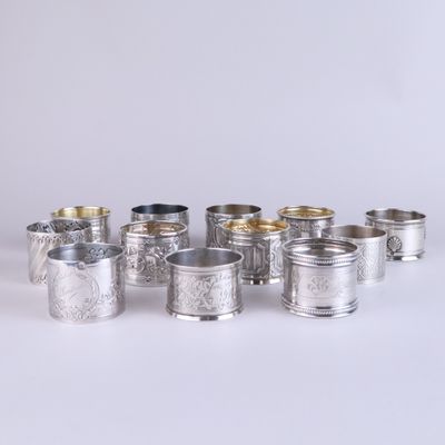 un ensemble composé de six tasses en argent et d'une cuillère en argent, posé sur une surface blanche