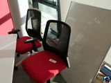 une chaise de bureau rouge et un bureau blanc dans une pièce