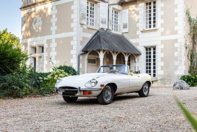 une voiture de sport blanche garée devant une grande maison