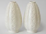 pair of white ceramic vases sitting on top of a white table