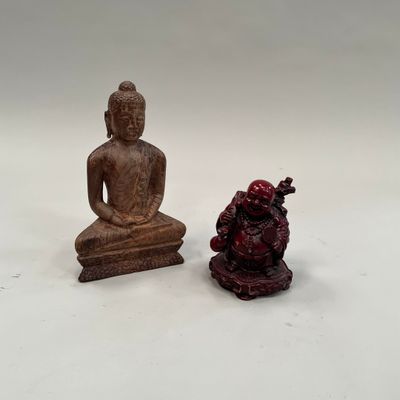 deux figurines de bouddhas assis l'un à côté de l'autre sur une surface blanche